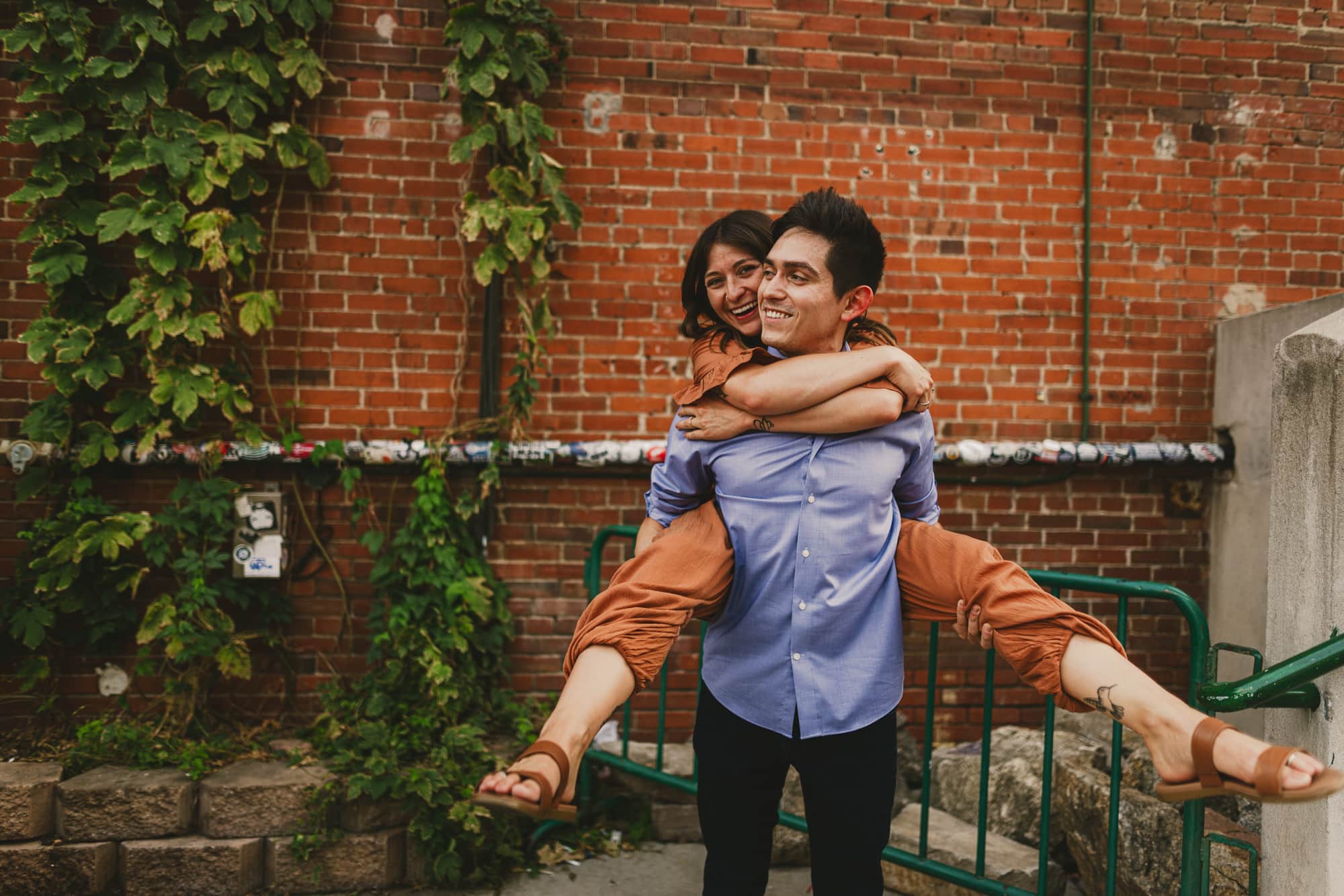 Couple giving each other a piggy back ride at their engagement session