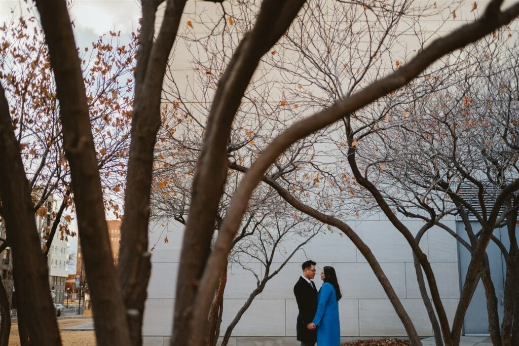 Couple posed artistically in winter trees outside the Lindsey-Flanigan Courthouse in Denver