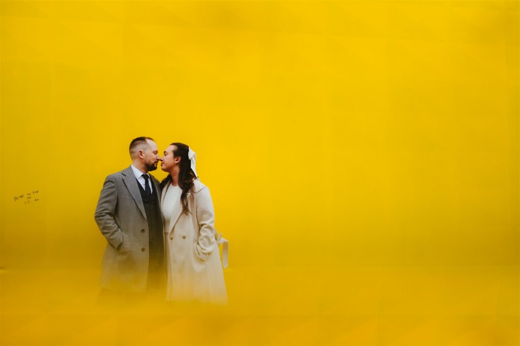 Couple silhouetted against a yellow wall near DPAC after their courthouse wedding in Denver.